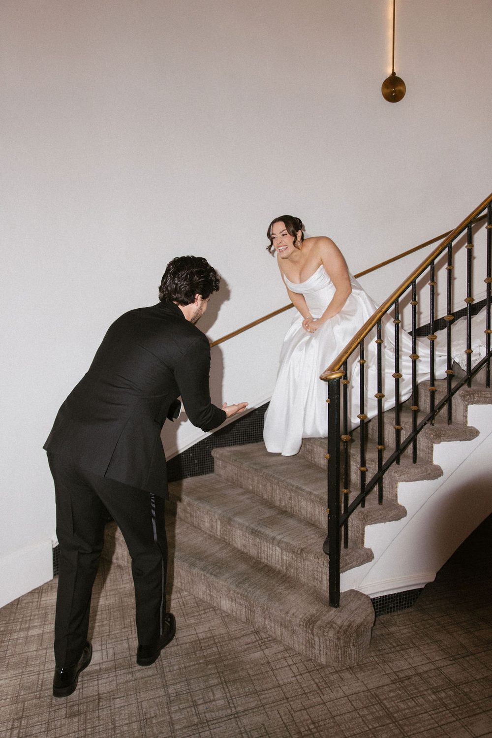 Bride descending stairs with groom waiting
